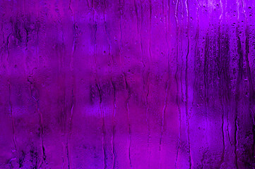 purple background of wet glass. drops of water