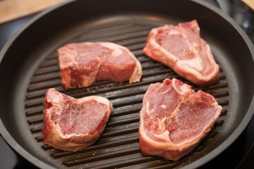 Lamb chops on a griddle pan cooking on a hob