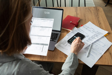 Crop woman calculating monthly expenses at home