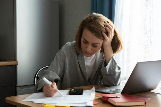 Focused student studying at table with papers and laptop
