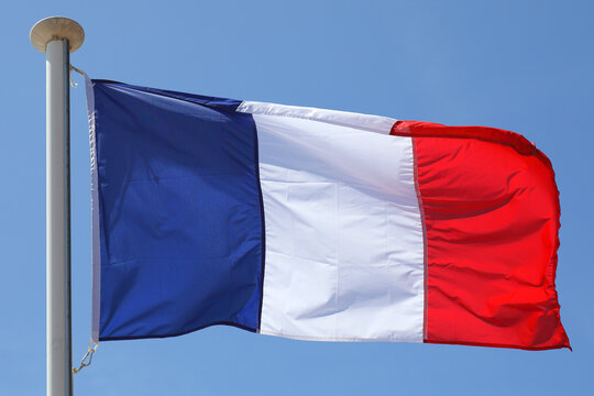 View of the flag of France flying in front of a blue sky