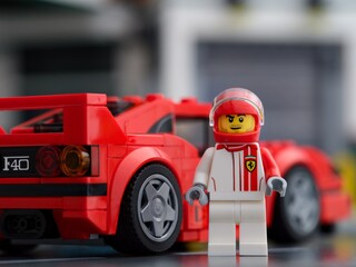 Fototapeta premium Tambov, Russian Federation - February 20, 2024 A Lego Ferrari F40 Competizione driver minifigure standing near back of his car by LEGO Speed Champions.