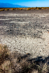 Dry yellow clay cracked in the sun with sand in the Californian desert, Death Valley National Park, California