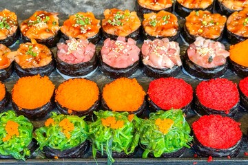 Colorful sushi selection on display, with red tobiko, green seaweed, orange masago, and chopped tuna, inviting street food lovers to enjoy authentic asian flavors