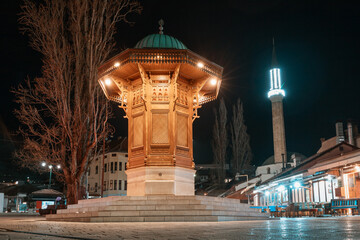 historic streets of Sarajevo's Bascarsija district at night, where the illuminated Sebilj fountain stands as a timeless landmark of Islamic architecture.