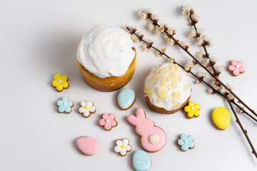 Easter cakes with Easter cookies and cherry blooming branches on white background