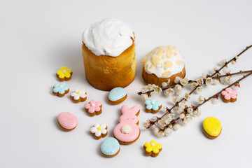 Easter cakes with Easter cookies and cherry blooming branches on white background