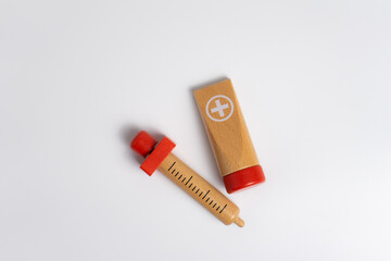 kids first aid kit wooden toys on white background, syringe and ointment tube