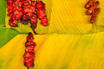 Sizzling skewers on a banana leaf highlight Asian street cuisine, with smoky aromas and vibrant...