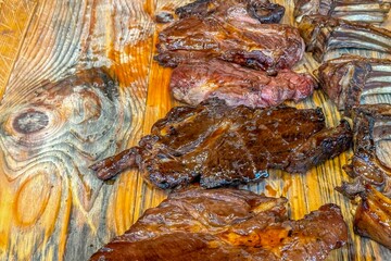 Obraz na płótnie Canvas Grilled steaks on a wooden board evoke rustic, outdoor cooking, promise a delicious taste experience, fitting for street food aficionados seeking authentic, hearty flavors