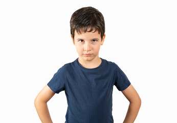 Cute little boy in white shirt looking at camera with angry expression. he is arms akimbo while standing against white background