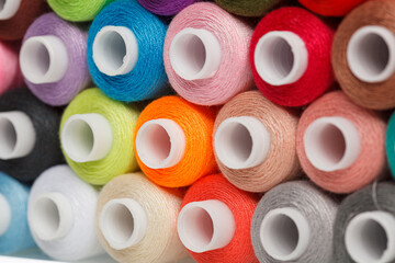 multi-colored spools of sewing thread on a white background