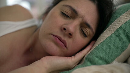 Tired woman close-up face overwhelmed by fatigue laid down on couch, close-up face of 30s female...