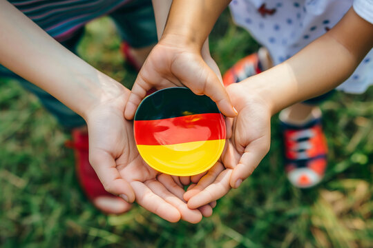 Happy people holding a small German flag toy in their hands. Generative AI