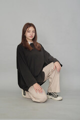Casually stylish young woman sitting, displaying a mix of modern and retro fashion. Symbolizes contemporary casual style.