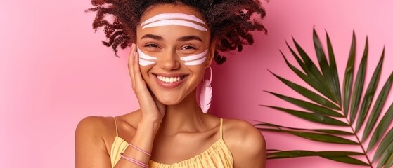   A woman holds a palm leaf before her, eyeliner adorning her eyes against a pink backdrop - obrazy, fototapety, plakaty