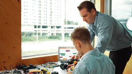 Caucasian teacher help student fixing car model and giving advise for programing system or coding...