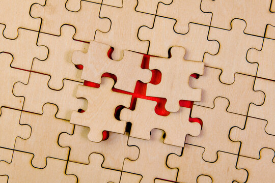 Interlocking Puzzle Pieces on Red Background: Strategy and Teamwork Concept