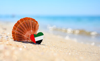 Sandy beach in United Arab Emirates. Flag of the United Arab Emirates in the shape of a heart and a large shell. A wonderful seaside resort.