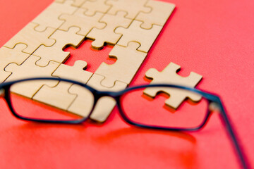 Glasses and jigsaw puzzle on red background Business concept