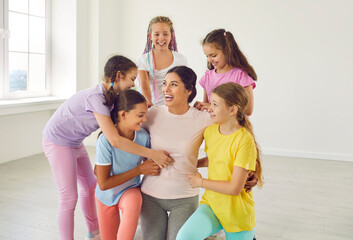 Portrait of cheerful happy active little girls sitting on the floor in choreography class with...