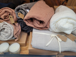 Rolls of fabric and textiles for sale are stacked on shelves in a store. Samples of natural textiles in warm colors on display at an exhibition. Blank kraft paper label mockup for market product