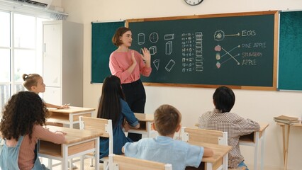 Smart teacher checking cute student homework while explaining idea at class. Attractive instructor...