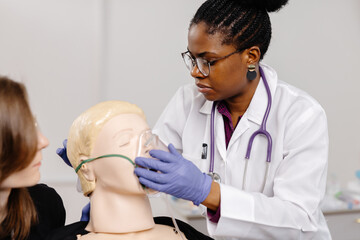 A doctor puts an oxygen mask on a mannequin at a first aid course