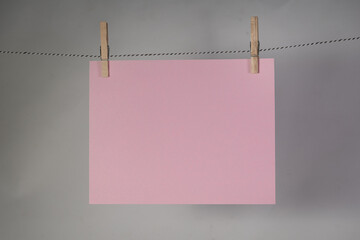 Pink blank sign hanging on clothesline with clothes pins gray background