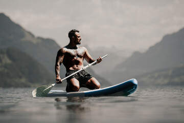 Man with paddle board. Man paddling on paddleboard. Muscular strong Hispanic man on sup board...