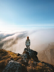 Woman traveler enjoying clouds view on mountain cliff edge in Norway, girl hiker climbing solo...