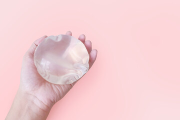 Silicone implant breast augmentation in holding on pink background, Surgery gel type and smooth...