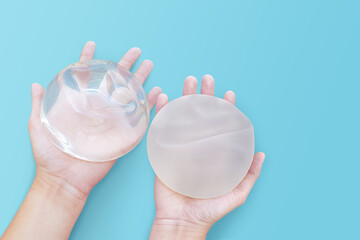 Silicone implant breast augmentation on space blue or turquoise background, Gel type rough and smooth touch surface in two hand, Medical equipment used in clinic or hospital.