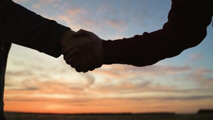 Handshake at sunset, silhouette in park field. Making deal teamwork cooperation successful joint...