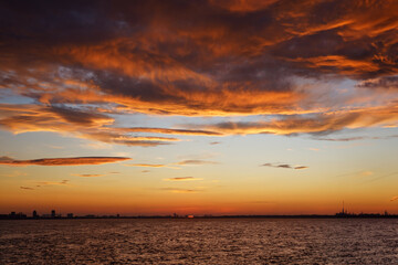 Fiery orange sunset sky with orange and red clouds near the sea. Beautiful sky.