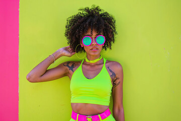 A woman wearing a neon green top and pink shorts stands outdoors. - 783369979