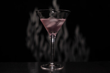 Cocktail drink with smoke in a martini glass on a table