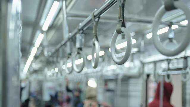 Panning shot of handrails of an electric commuter train as it stops at a station in Jakarta, Indonesia, during the day. Train passenger passing by.