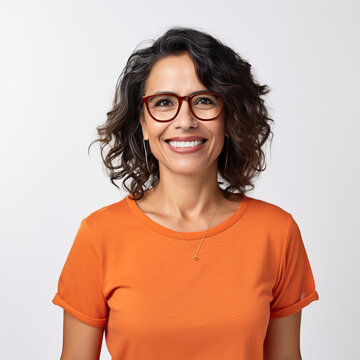 A woman wearing an orange shirt and glasses is smiling. She is wearing a necklace and has her teeth showing