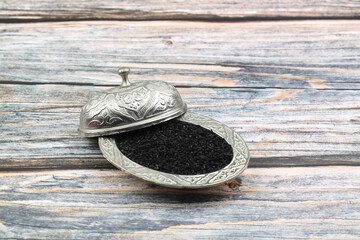 Black cumin seeds and essential oil with bowl and wooden shovel or spoon. Nigella Sativa in glass...