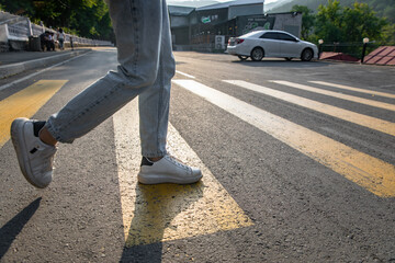 Man's legs crossing the road, yellow lines stock photo