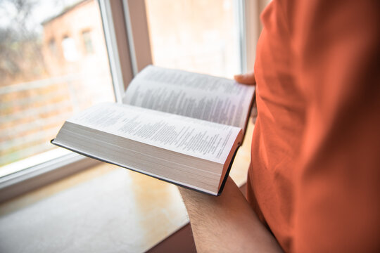 Man reading bible near window, spiritual concept, stock photo