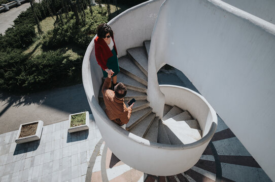 Two professional businesspeople having an informal meeting on a modern spiral staircase outside an office building