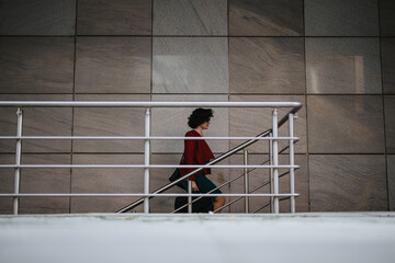 Professional and determined businesswoman in stylish attire ascending steps outside a contemporary building