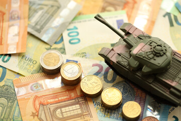 Many euro banknotes and tank. Lot of bills of European union currency and green tank close up