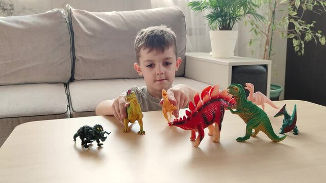 a boy lying on the floor plays with his favorite toys, bright figures of dinosaurs. happy children