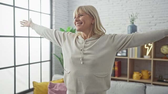 Happy mature woman embracing freedom with arms wide open in her modern white-themed living room.