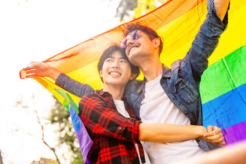 Multi-ethnic gay couple celebrating diversity raising lgbt flag