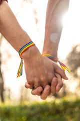 Gay men with rainbow bracelets holding hands