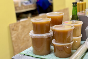 Stacks of plastic containers with honey at farmers food market. There are a lots of jars with sweet natural honey of various types and colors for sale. Close-up